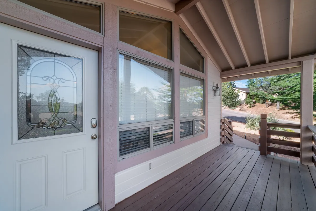 The image showcases the home's beautiful exterior featuring a decorative stained glass door, large windows that promise abundant natural light inside, and a welcoming covered porch. The porch offers a serene space perfect for morning coffees or evening relaxation while taking in the peaceful neighborhood setting.